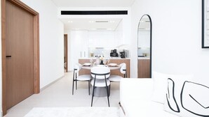 A modern hotel room with a dining area, a large mirror, and a white sofa. - Dubai Luxury Apartment w/ Pool & Gym, Near Cafes (Dubai)