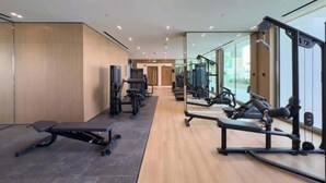 A modern gym with various exercise equipment, a bench, and a mirrored wall. - Dubai Luxury Apartment w/ Pool & Gym, Near Cafes (Dubai)