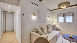 Un salon moderne avec un canapé, une table basse et une lampe. On y trouve une porte qui donne sur une autre pièce et une fenêtre avec des rideaux.