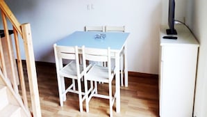 A small room with a blue table and white chairs, a wooden staircase, and a white cabinet with a television. - Apartment on Ile D'oleron Near the Beach (Saint-Georges-d'Oleron)