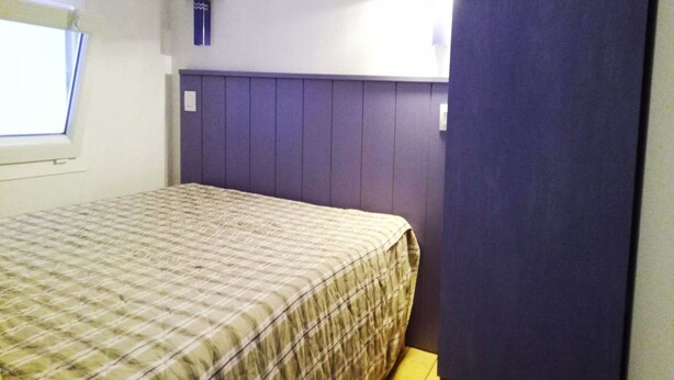 A room with a bed, a window, a wall-mounted lamp, and a door. - Apartment on Ile D'oleron Near the Beach (Saint-Georges-d'Oleron)