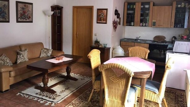 A living room with a sofa, coffee table, and chairs, a dining area with a table and chairs, and a kitchen with cabinets and appliances. - Apartment in Lennestadt for 2 Person (Lennestadt)