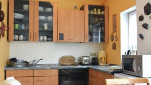A kitchen with wooden cabinets, a dishwasher, a toaster, a coffee maker, and a microwave. - Apartment in Lennestadt for 2 Person (Lennestadt)