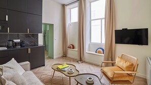 Un salon moderne avec un canapé, une table basse, un téléviseur et un fauteuil.