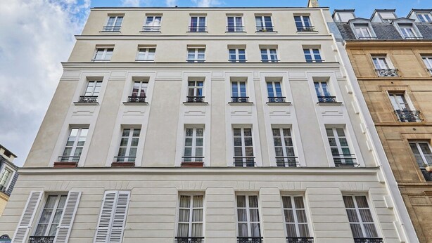 Un immeuble à plusieurs étages, doté de façades blanches et de nombreuses fenêtres.