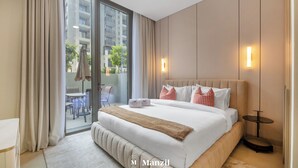 A hotel room with a large bed, a small table, and a view of the outside. - Manzil - Cozy 1BR Waterfront Apartment  (Dubai)