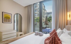 Een hotelkamer met een bed, een bureau, een stoel, een groot raam en uitzicht op buiten.