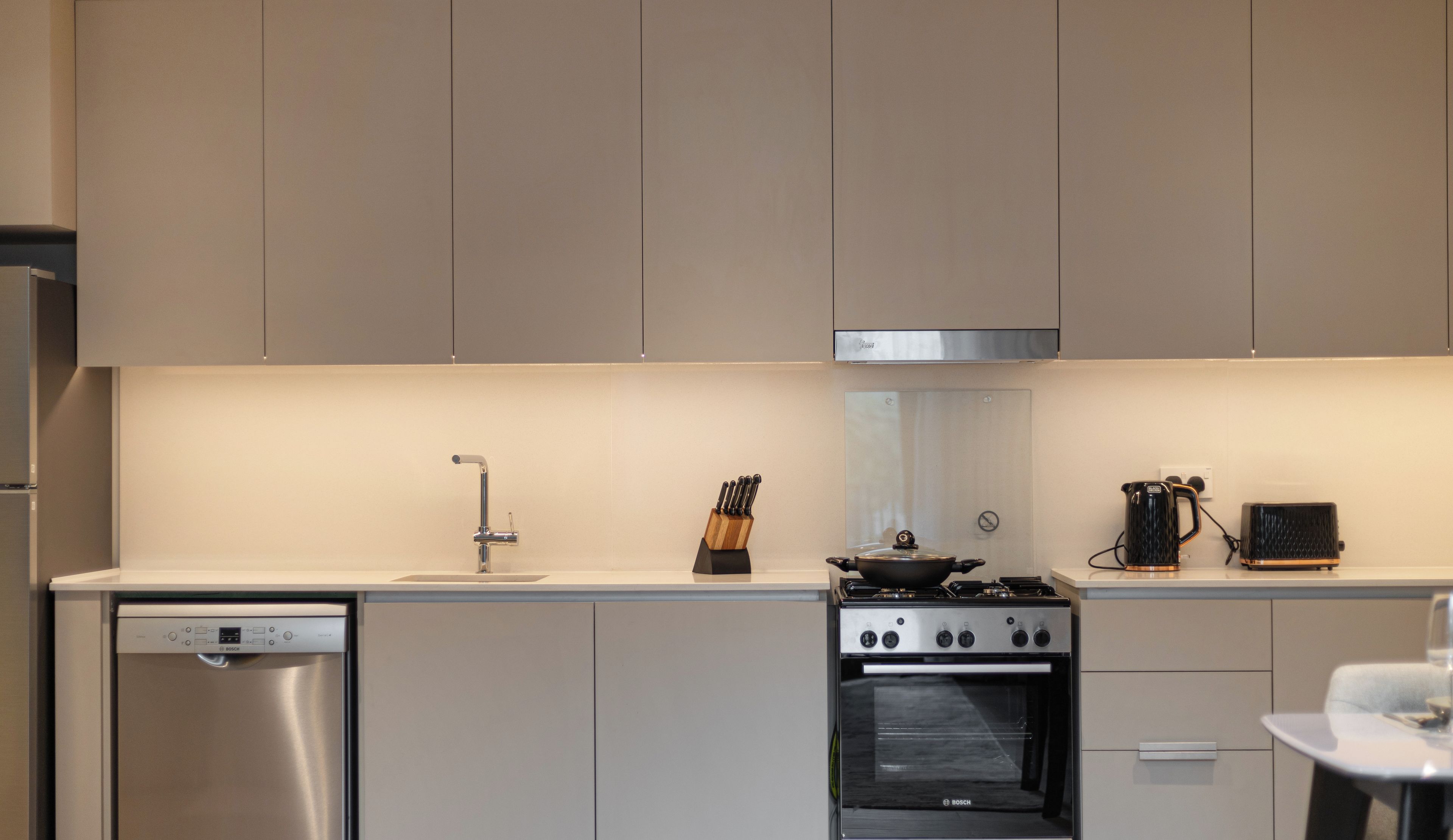 Une cuisine moderne équipée d’appareils électroménagers en acier inoxydable, notamment un lave-vaisselle, une cuisinière et un four.