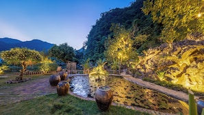 Un jardin paisible avec un bassin, un sentier de pierres et de grands vases.