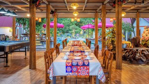 Un restaurant avec vue sur la piscine, un plafond en bois et des tables dressées pour le dîner.