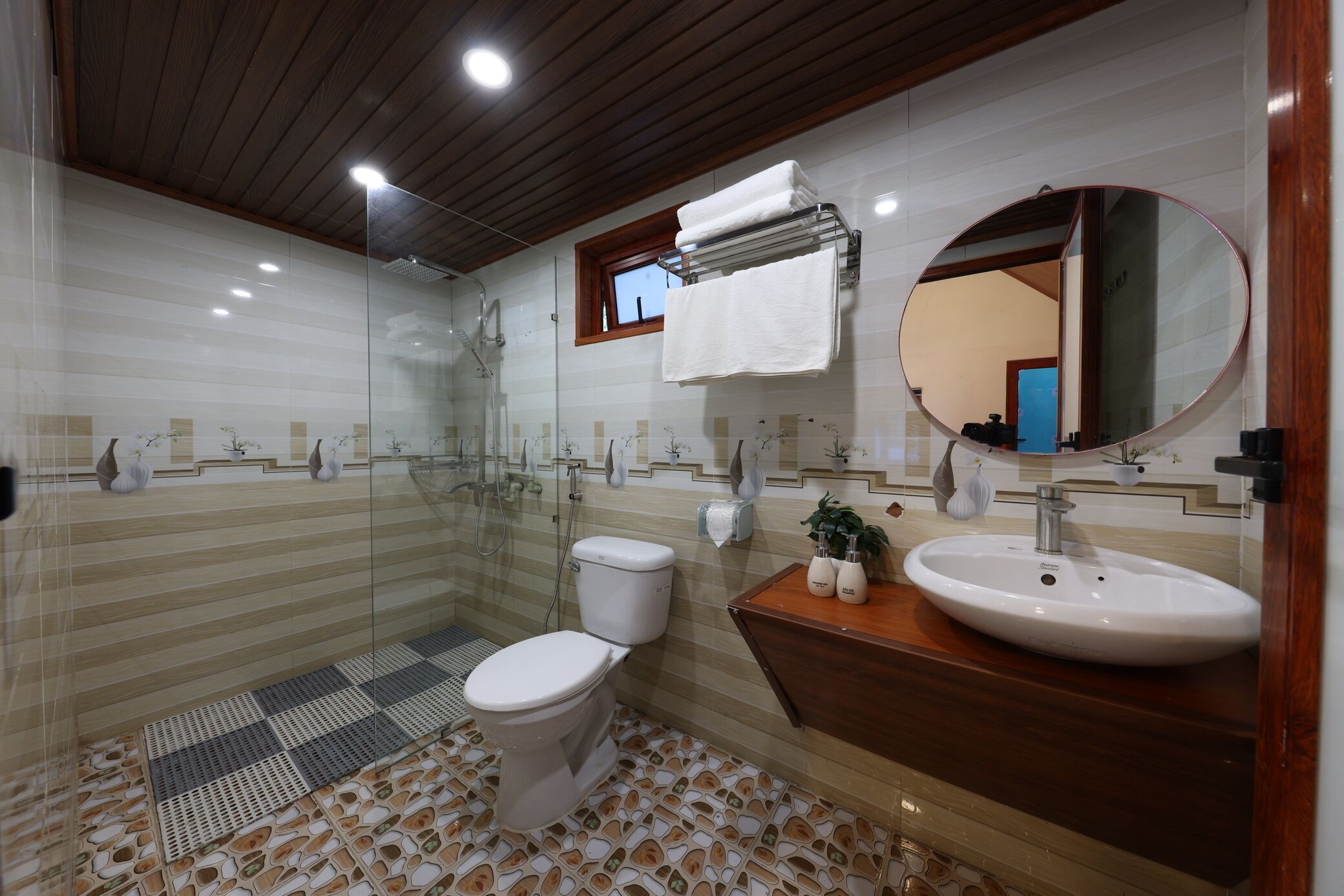 Uma casa de banho moderna com cabine de chuveiro em vidro, sanita, lavatório e toucador.