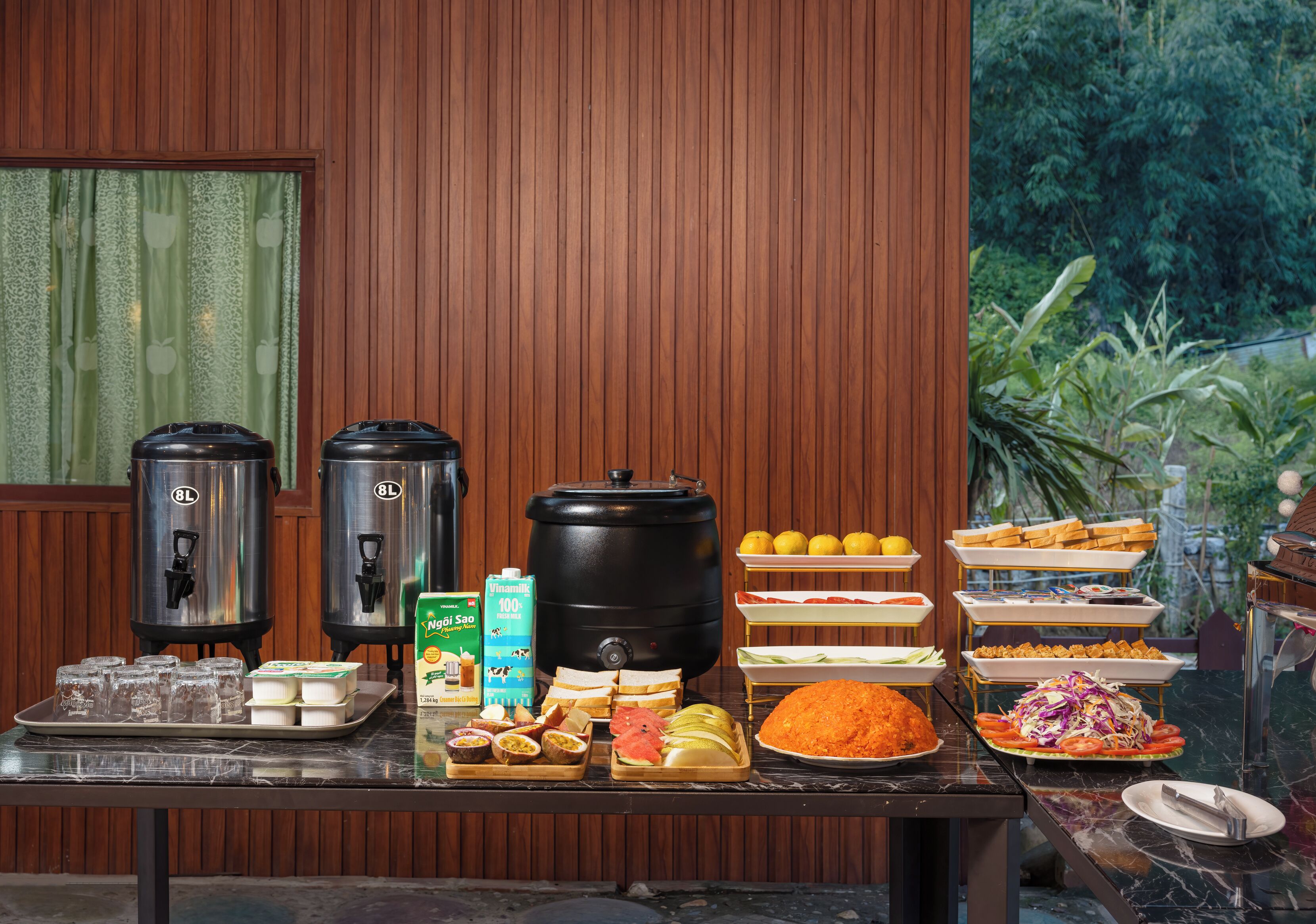 Un buffet proposant une variété de plats, un coin café et une grande marmite noire.
