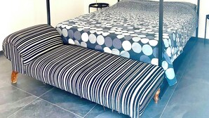 Una cama con dosel con un edredón estampado circular, un banco a juego y una mesita de noche con una lámpara.
