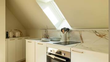 Eine Küche mit Oberlicht, weißen Schränken, einem eingebauten Backofen und einer Marmor-Spritzschutzwand.