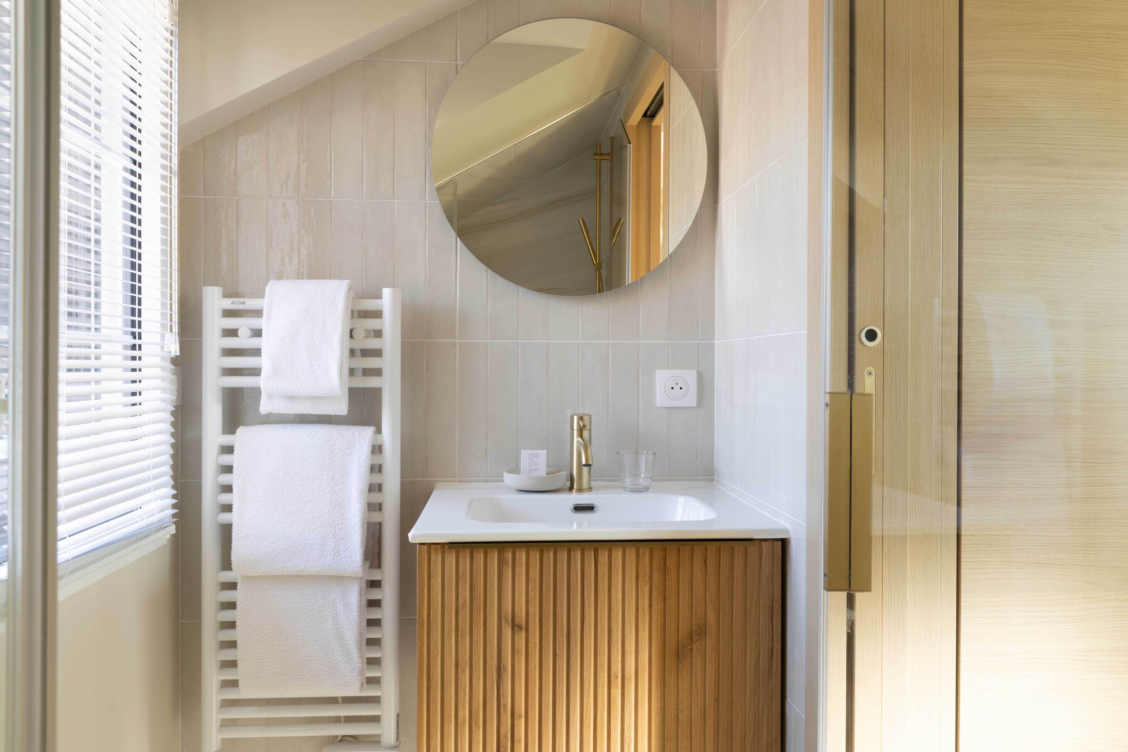 A bathroom with a white sink, a mirror, and a towel rack.