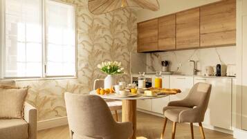 A modern kitchen with wooden cabinets, a dining table with chairs, and a breakfast setup.