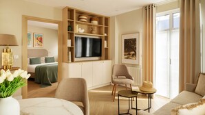 A modern living room with a flat-screen TV, a sofa, a chair, a small table, and a bookshelf. - Villa Léa, l’écrin du Fer à Cheval (Trouville-sur-Mer)