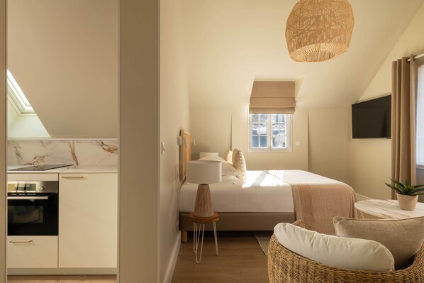 A bedroom with a bed, bedside table, lamp, and a view of the outside. - Villa Léa, l’écrin du Fer à Cheval (Trouville-sur-Mer)