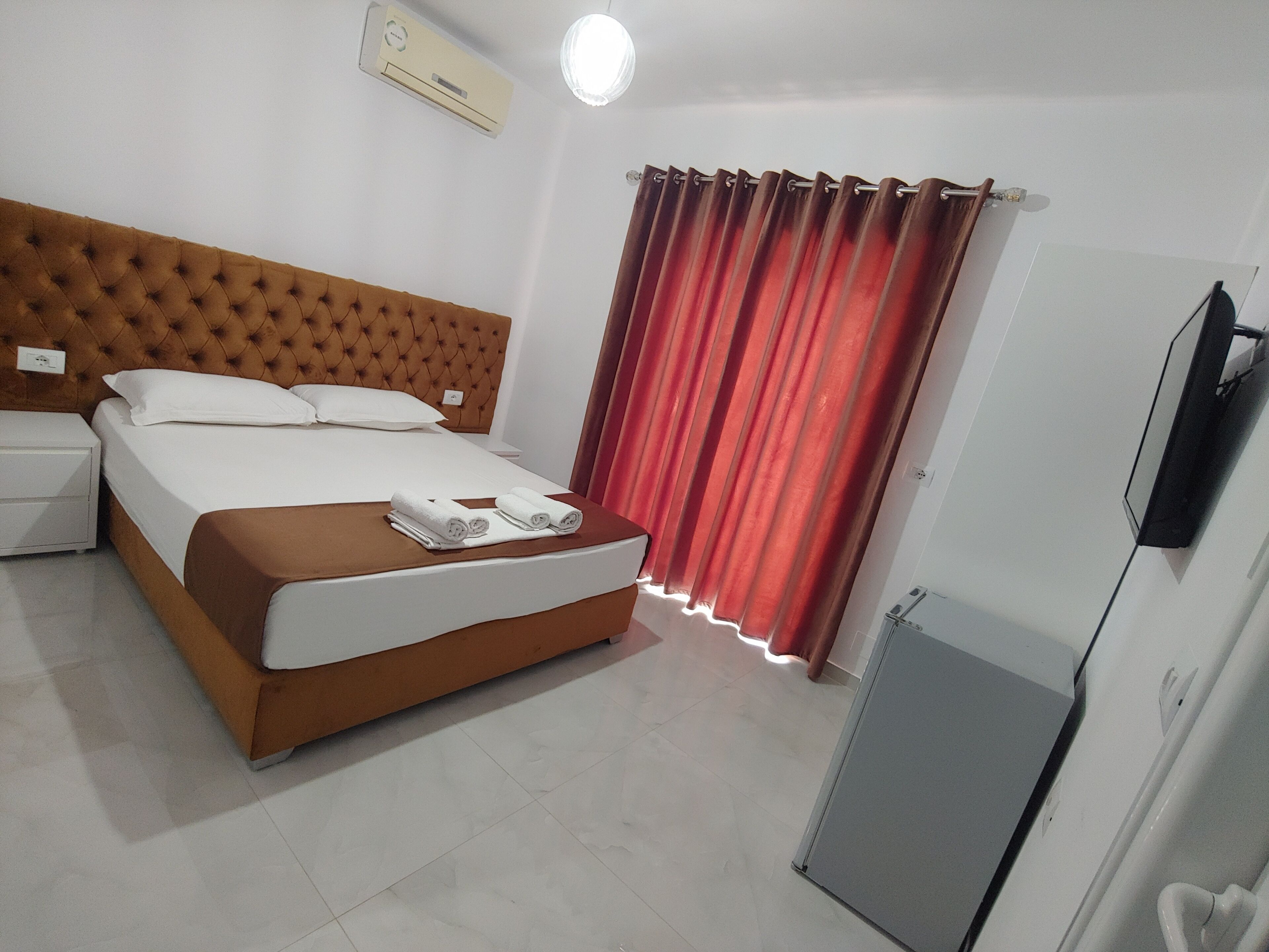 Een hotelkamer met een bed, nachtkastje, televisie en garderobe.