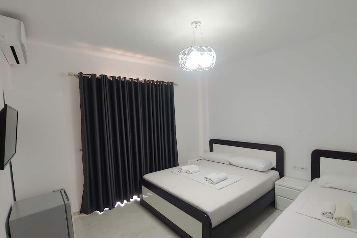A modern bedroom with a bed, bedside tables, and a unique hanging light fixture.