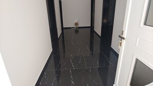Un couloir doté d’un sol en marbre noir brillant, de murs blancs et de portes de part et d’autre.