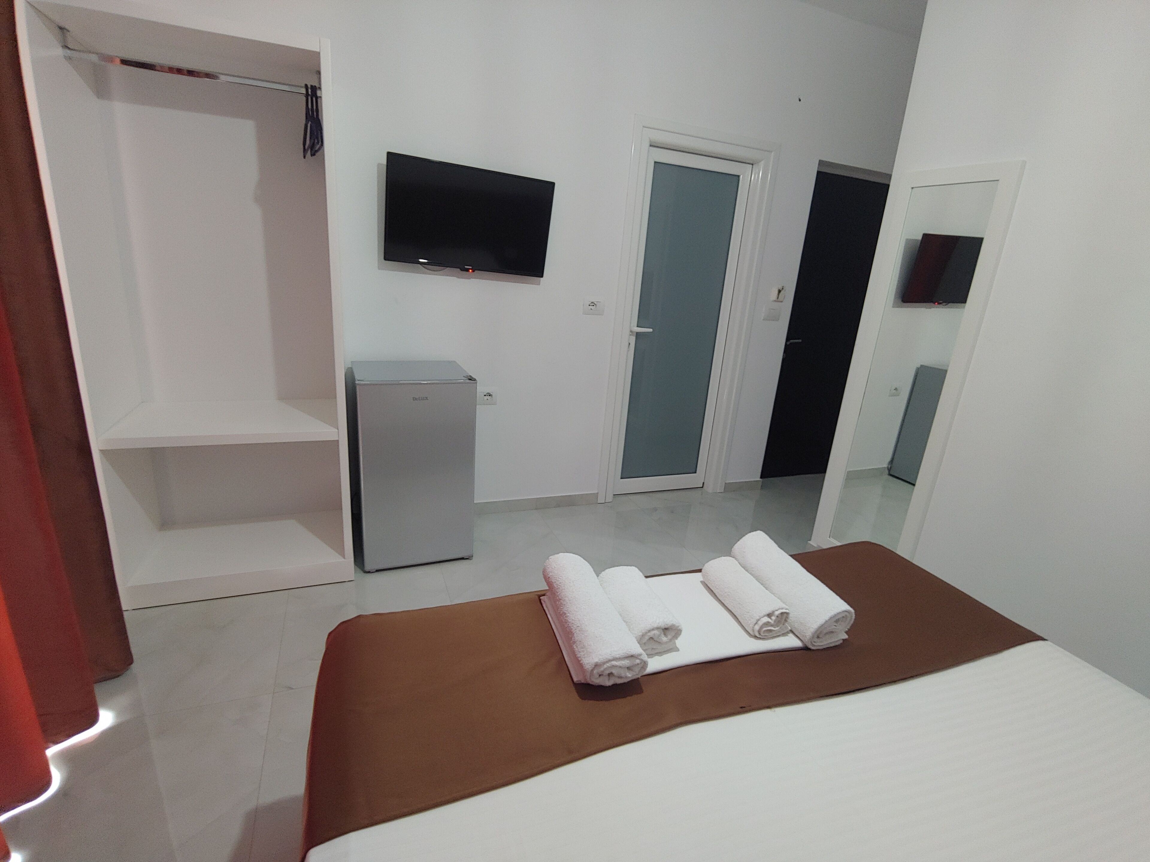 Habitació d'hotel amb llit, televisió, armari i nevera petita.