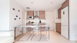 A modern kitchen with a central island, stainless steel appliances, and wooden cabinets. - Duplex in Sitges with sea views, parking, terrace, balcony (Sitges)