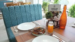 Una mesa de comedor con platos, cubiertos, un vaso de jugo de naranja y una botella.
