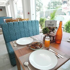 A dining table with plates, cutlery, a glass of orange juice, and a bottle.