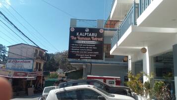 A signboard for 'Kalpataru The Kumau Retreat' hotel and restaurant, listing amenities like a 24x7 power supply and breakfast.