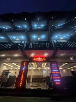 Un edificio a più piani con balconi, un cartello con la scritta 'CHULAH THE KITCHEN' e un elenco di cucine tra cui indiana, cinese, sud indiana, continentale e chaat.