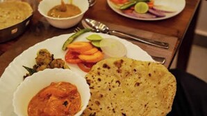Una mesa de comedor con varios platos, incluyendo un pan plano, un recipiente con salsa y un plato de verduras.