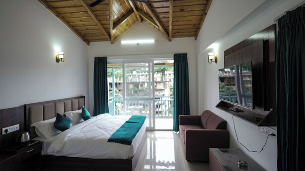 Una habitación de hotel con cama, televisor, sofá y balcón con vistas.