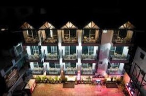 A multi-story hotel with balconies, a courtyard, and a pool area. - Kalptaru The Kumaun retreat (Sukha)