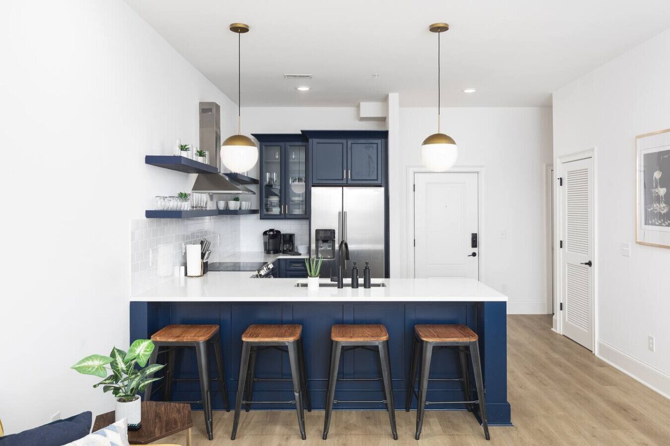A modern kitchen with a central island, bar stools, and pendant lighting.
