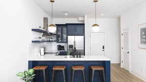 A modern kitchen with a central island, bar stools, and pendant lighting. - Sleeps 32, only 10 minutes to Broadway, 4 Condos Side-by-Side (Nashville)