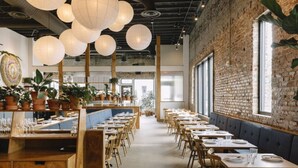 A restaurant with a brick wall, wooden tables, and hanging paper lanterns. - Sleeps 32, only 10 minutes to Broadway, 4 Condos Side-by-Side (Nashville)