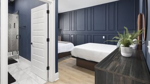 A bedroom with a dark blue wall, a white door, a bed, a bedside table with a plant, and a small window. - Sleeps 32, only 10 minutes to Broadway, 4 Condos Side-by-Side (Nashville)
