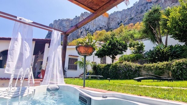 Un área de piscina con una pérgola de madera, un jacuzzi y vistas a un paisaje montañoso.