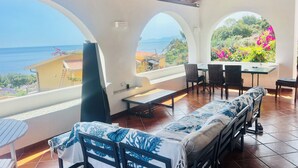 Una terraza con vistas al mar, que incluye un sofá, sillas y una mesa.