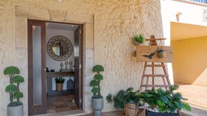 A building entrance with a wooden door, a circular mirror, and potted plants. - Es Refugi de les Aguiles (Lloseta)
