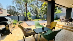An outdoor patio with a grill, chairs, and a table.