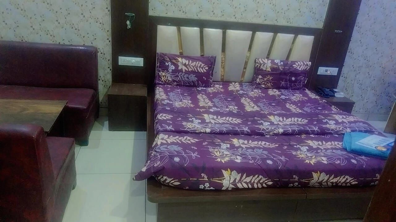 A room with a bed, a sofa, and a nightstand.