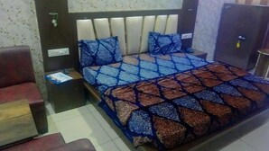 Ein Hotelzimmer mit einem Bett, einem Nachttisch, einem roten Sessel und einem Holzschrank.