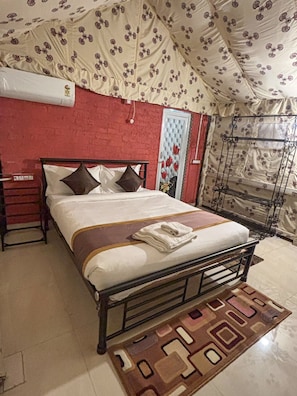 A bed with a metal frame, a patterned curtain, and a red wall. - Salboni Retreat (Jhargram)