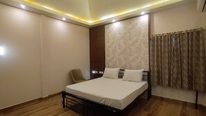 A bedroom with a bed, a chair, a wardrobe, and a window with curtains.