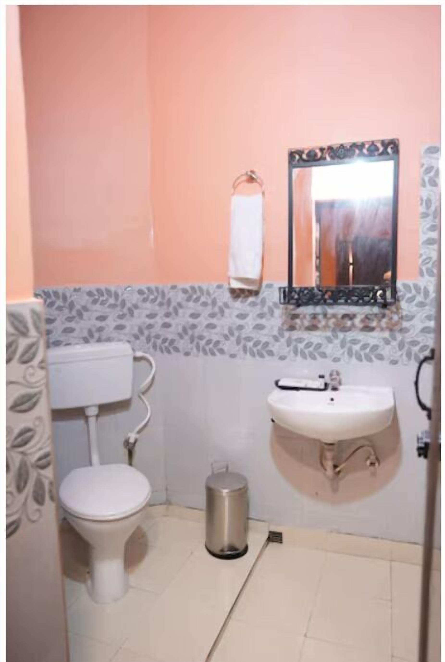 A small bathroom with a toilet, sink, and mirror.