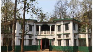 A multi-story building with a central entrance, surrounded by trees.