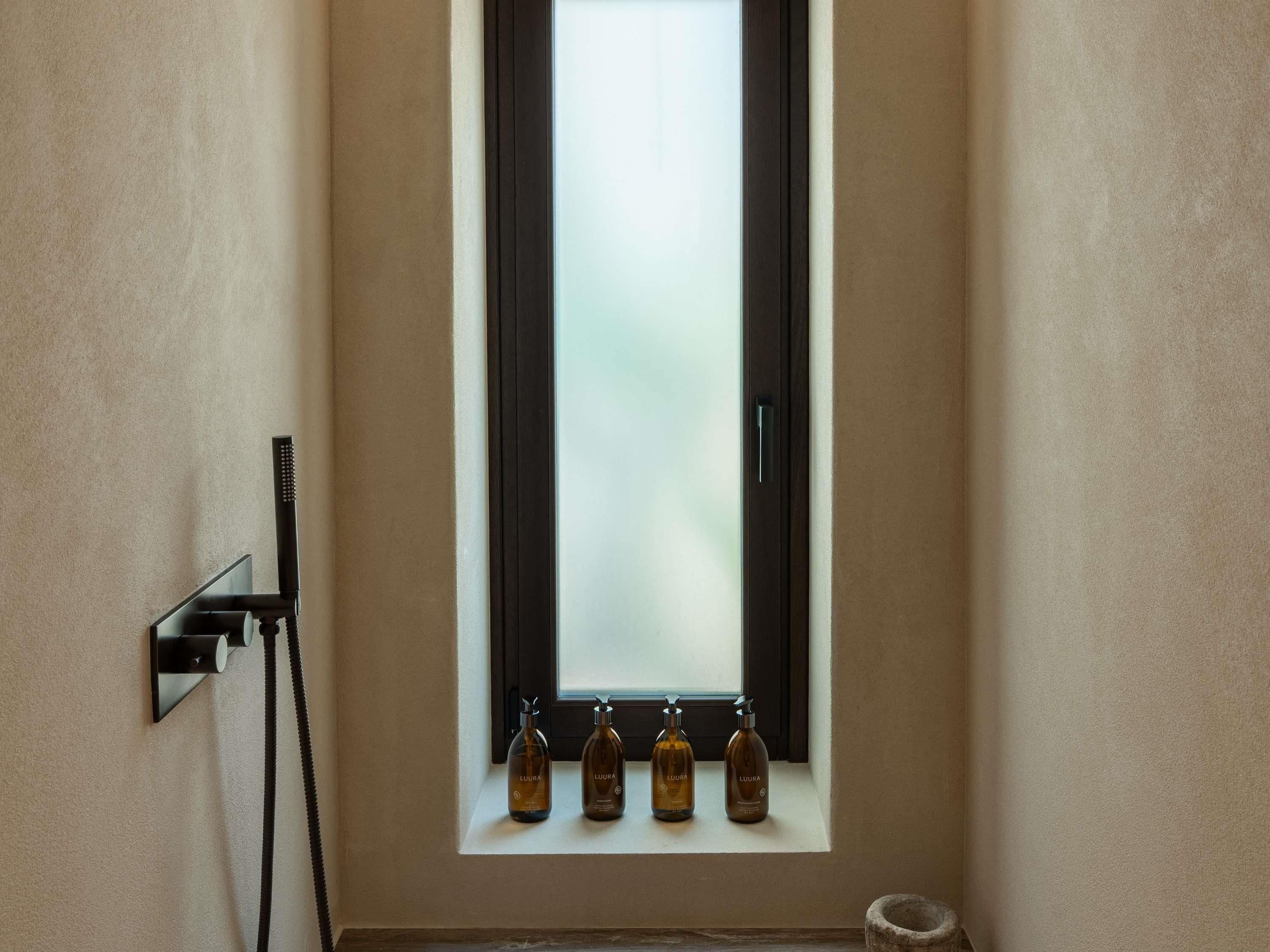 Une salle de bain avec une fenêtre, un porte-serviettes et trois flacons de lotion.