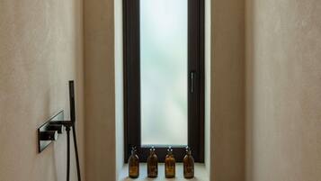 Une salle de bain avec une fenêtre, un porte-serviettes et trois flacons de lotion.